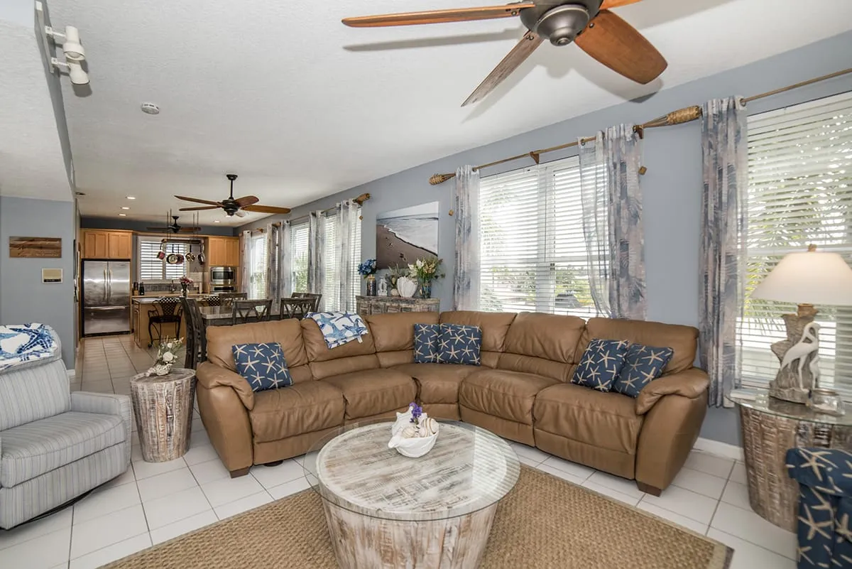 Open living room with brown leather couch and full kitchen