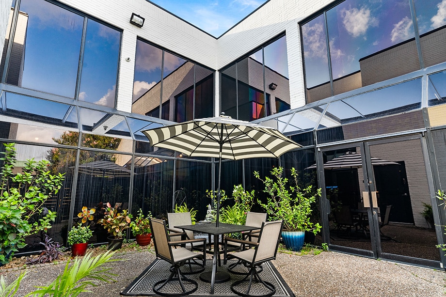 Outdoor patio with table, umbrella, and lush potted plants
