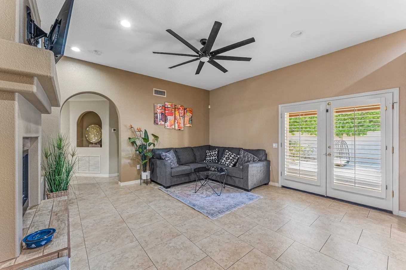 Living room with sectional sofa, fireplace, television, and patio doors.