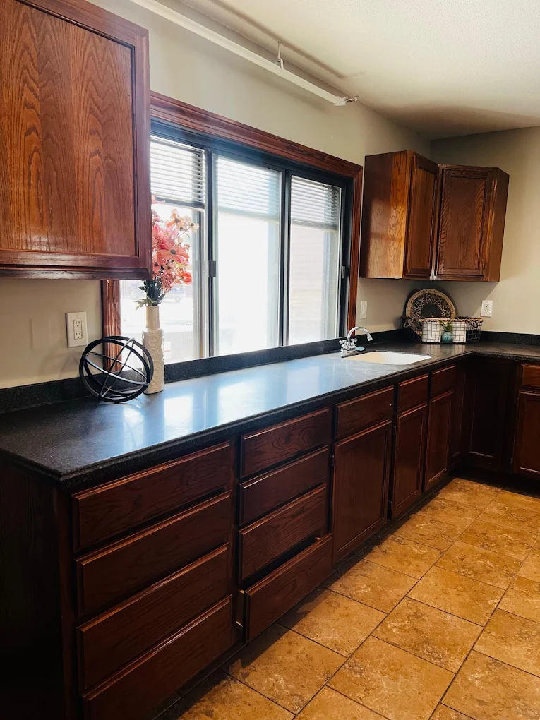Kitchen with wooden cabinets, dark countertops, and a sink