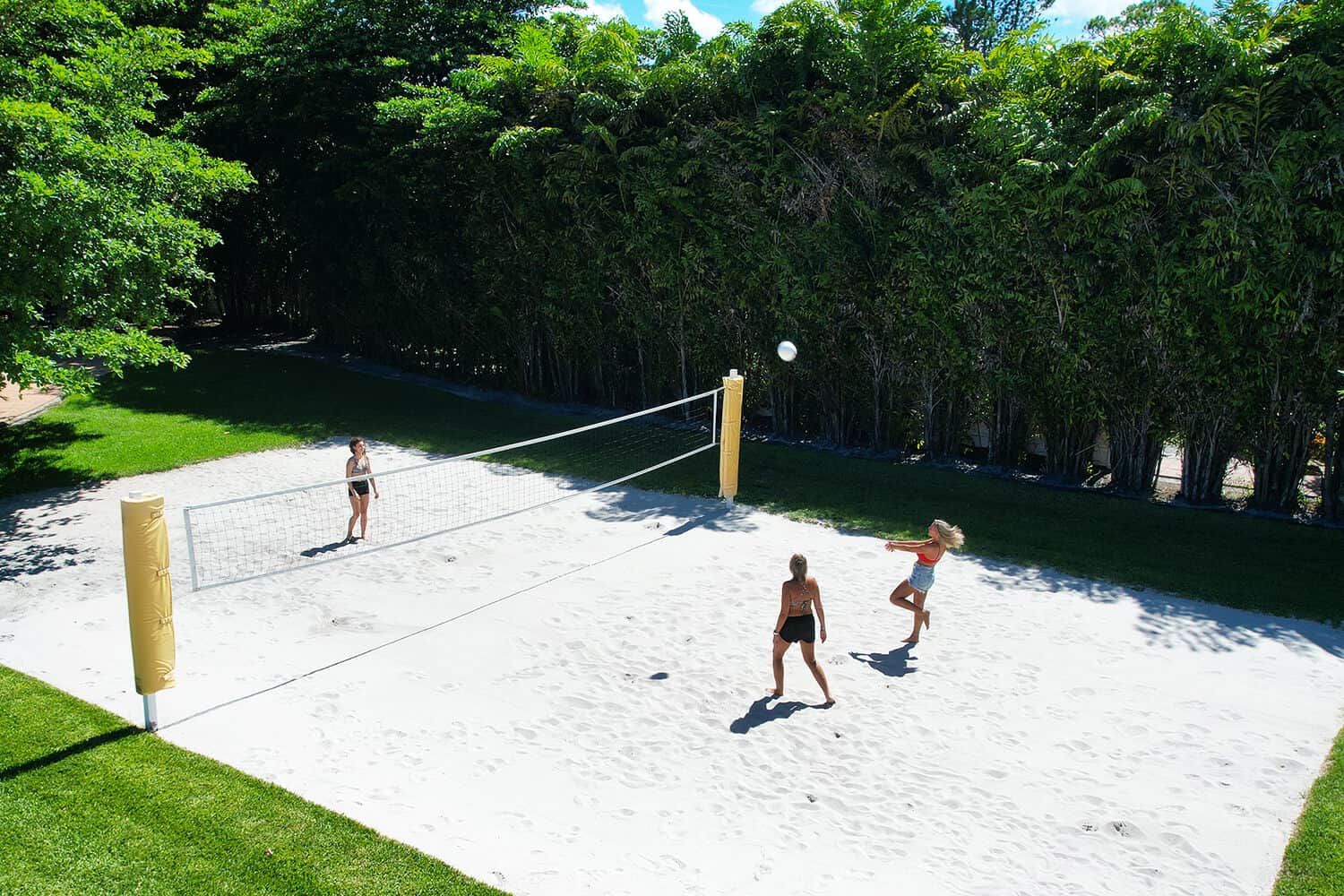 People playing volleyball on sand court