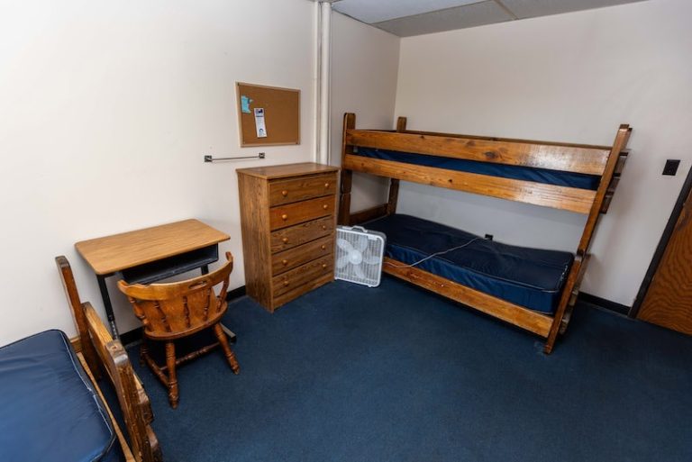 Small dorm room with bunk beds and desk