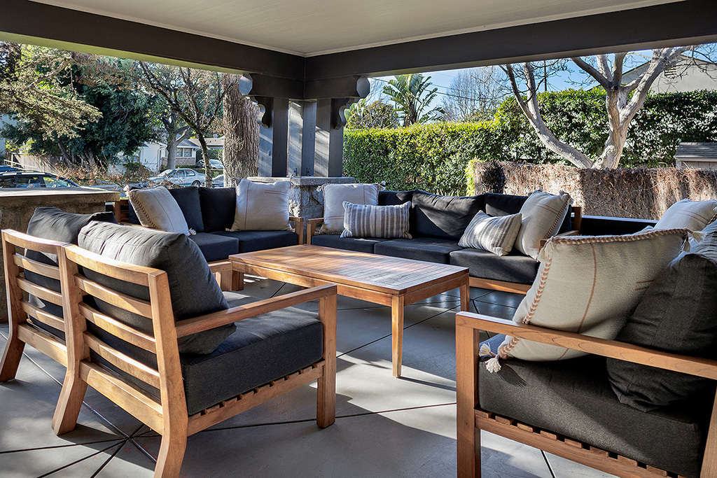 Outdoor porch with wooden chairs and sofas arranged around table