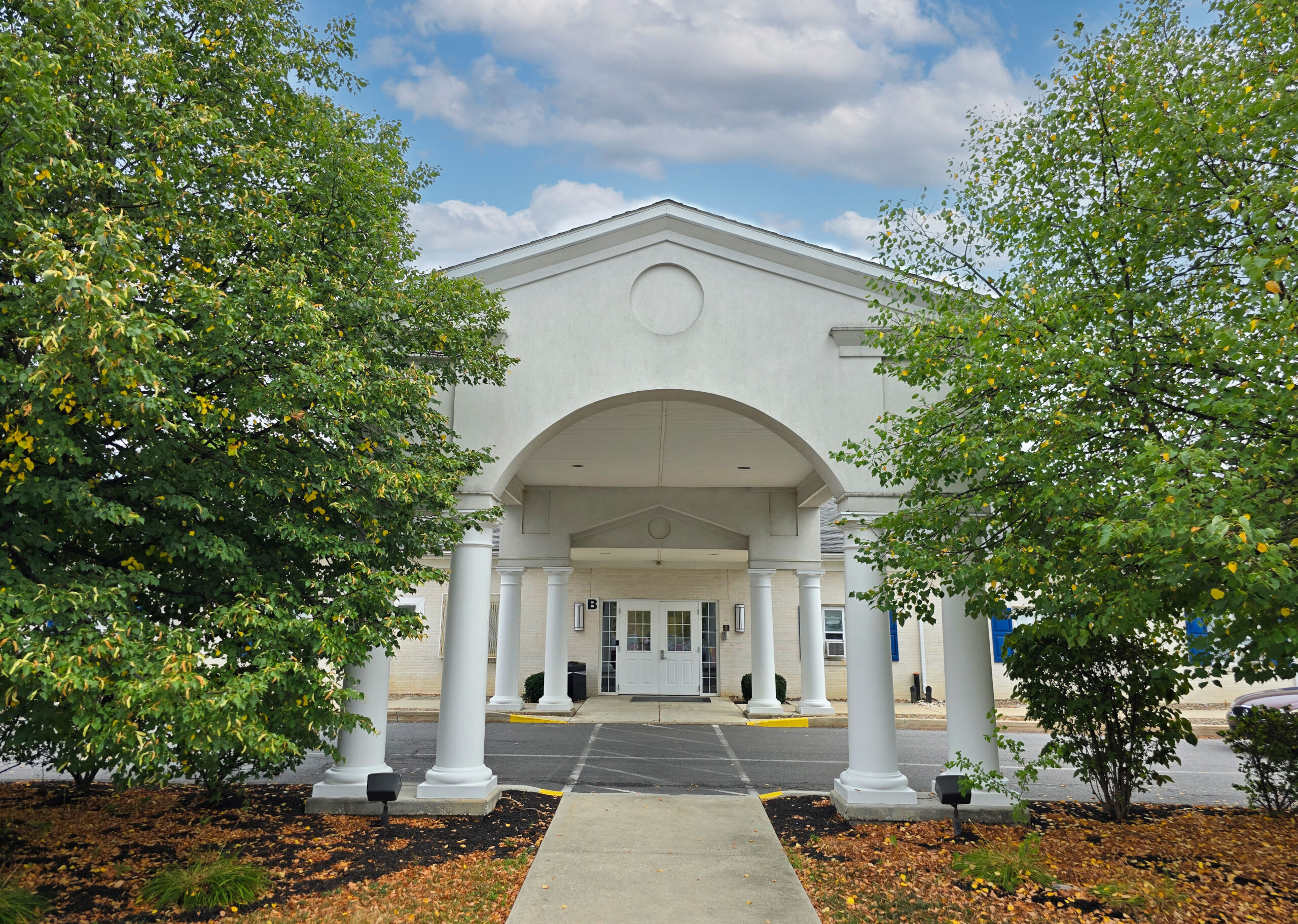 White entrance with large pillars and arched roof