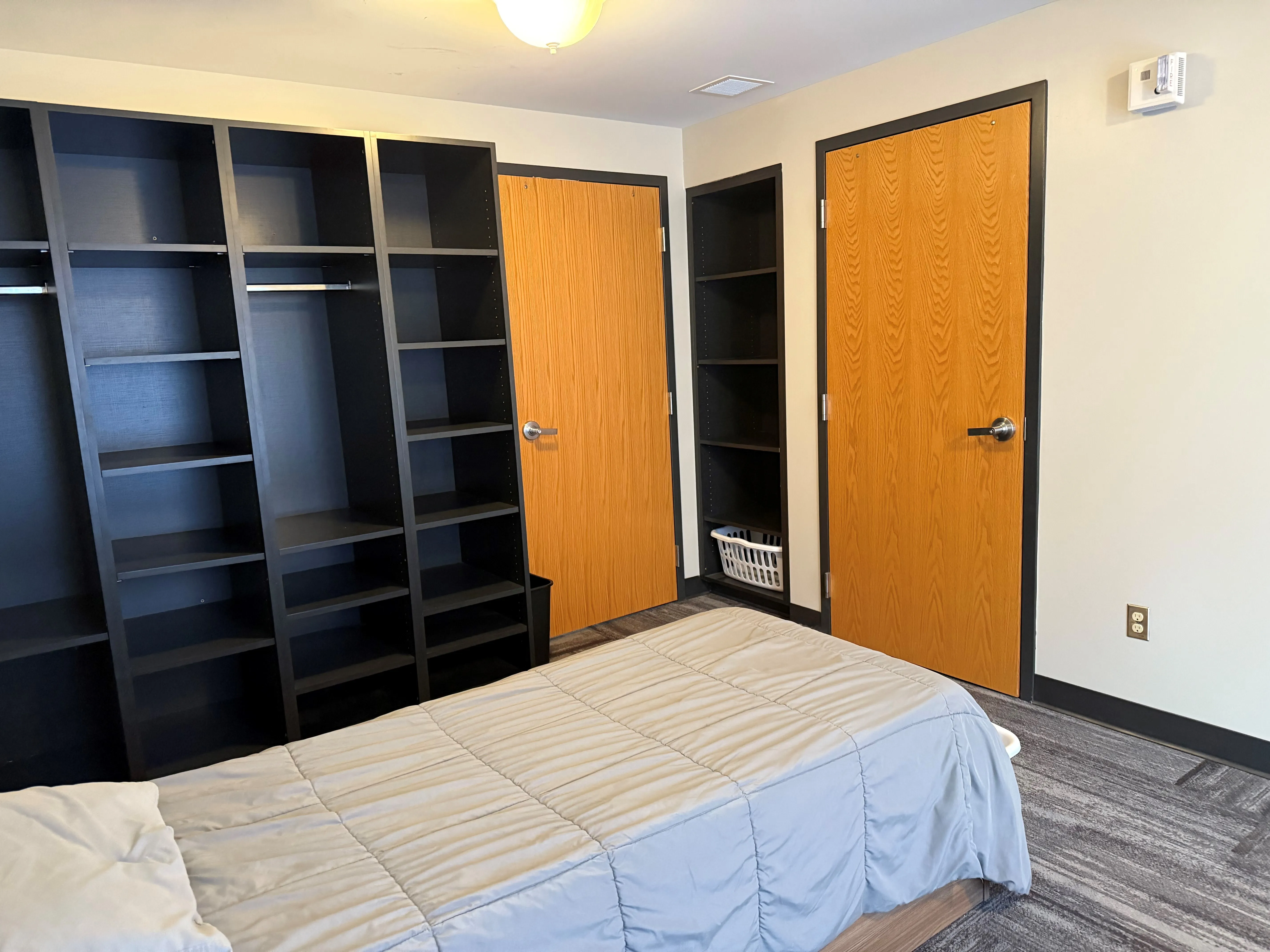 Single bed with open closet and wooden doors in room