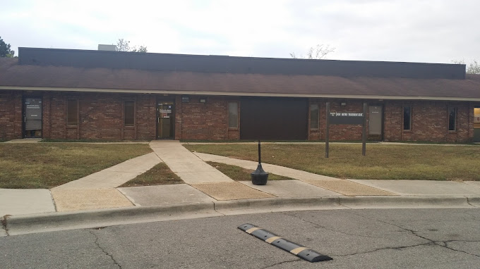 Exterior of facility with accessible pathways and signage on lawn post.
