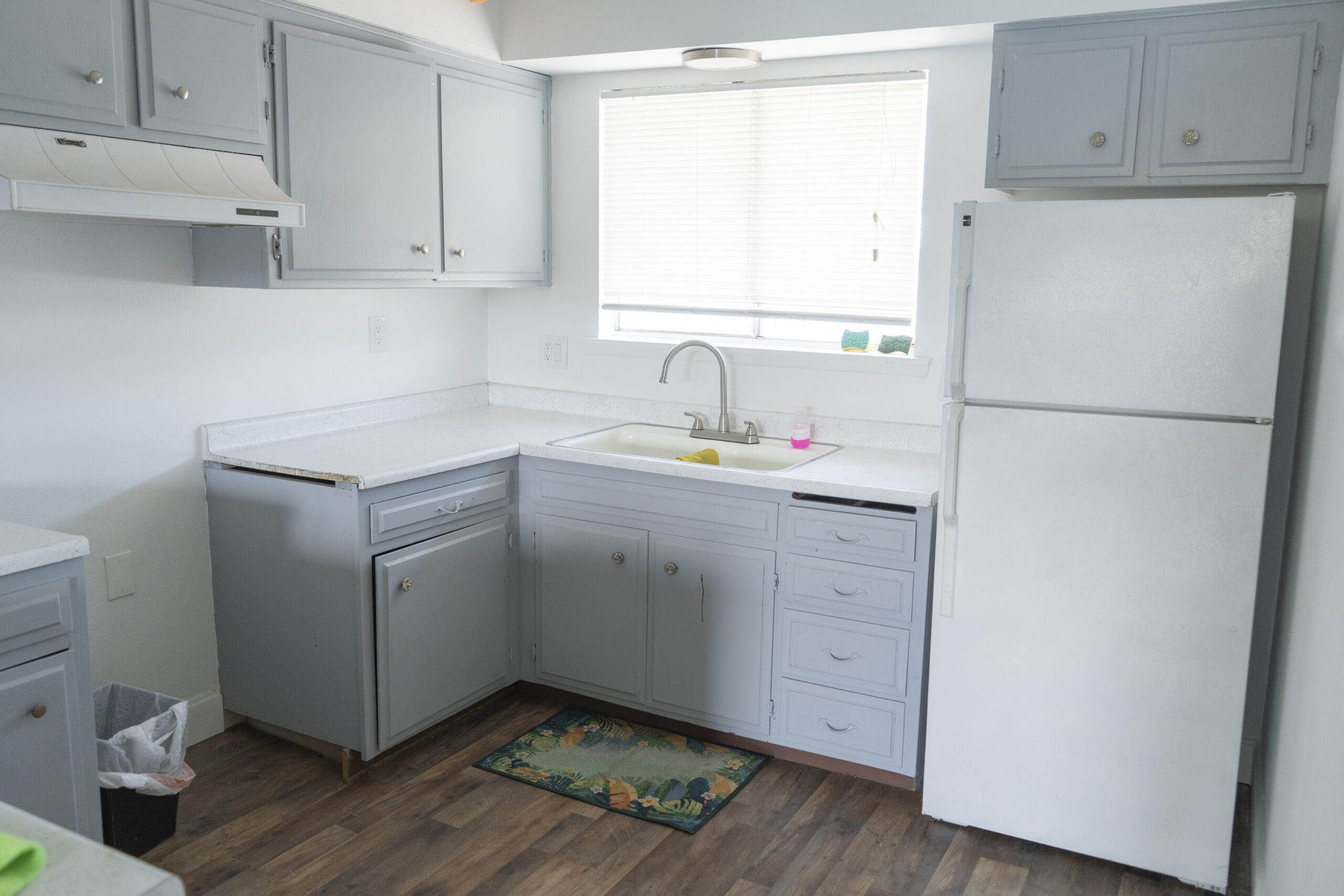 Compact kitchen with light blue cabinets and white fridge