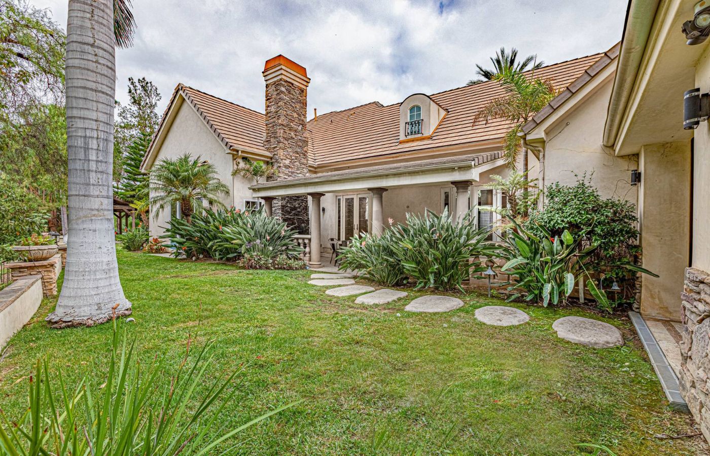Lush garden with stone path leading to a covered patio area.