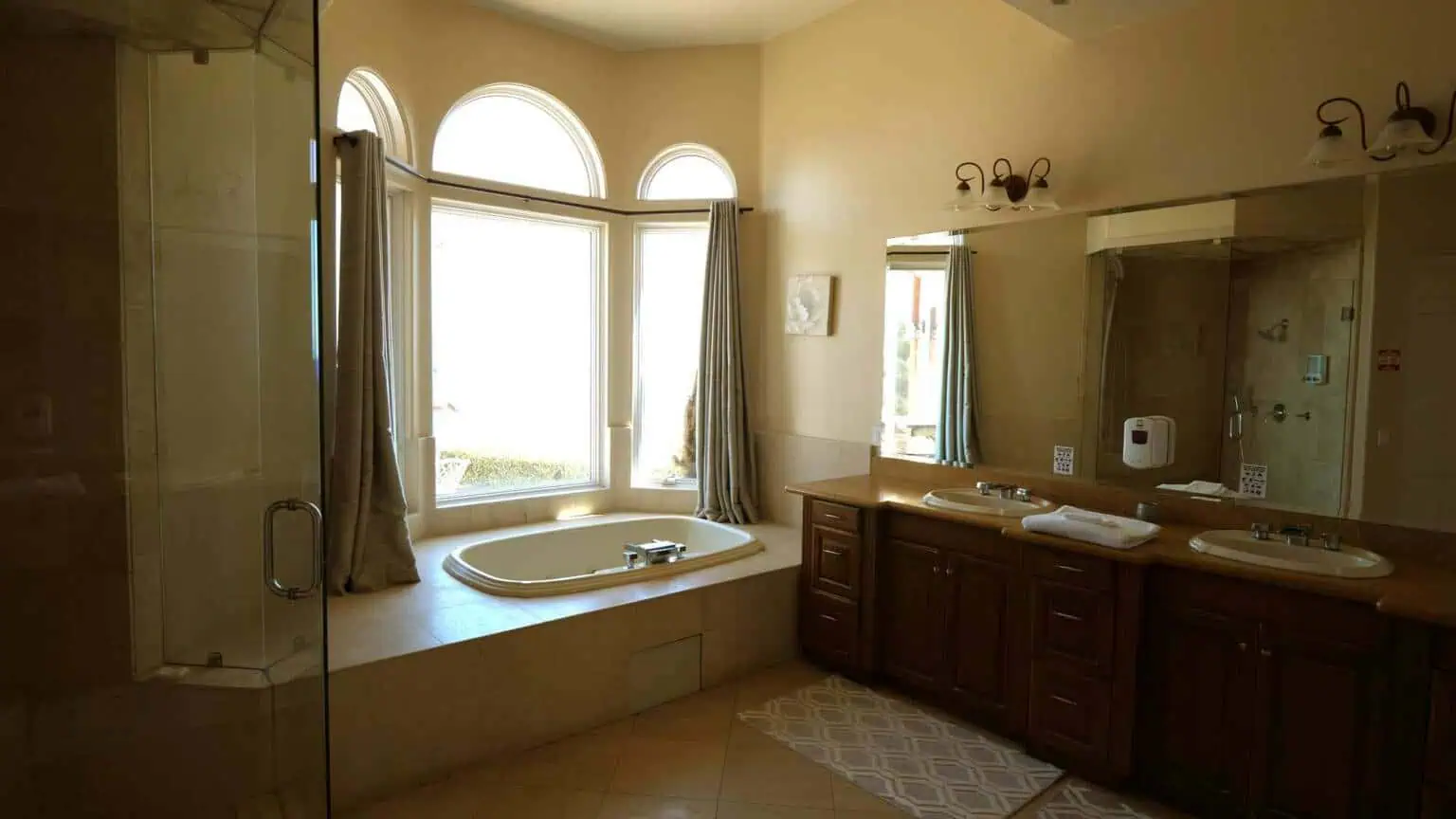 Bathroom with soaking tub, double vanity, and arched windows