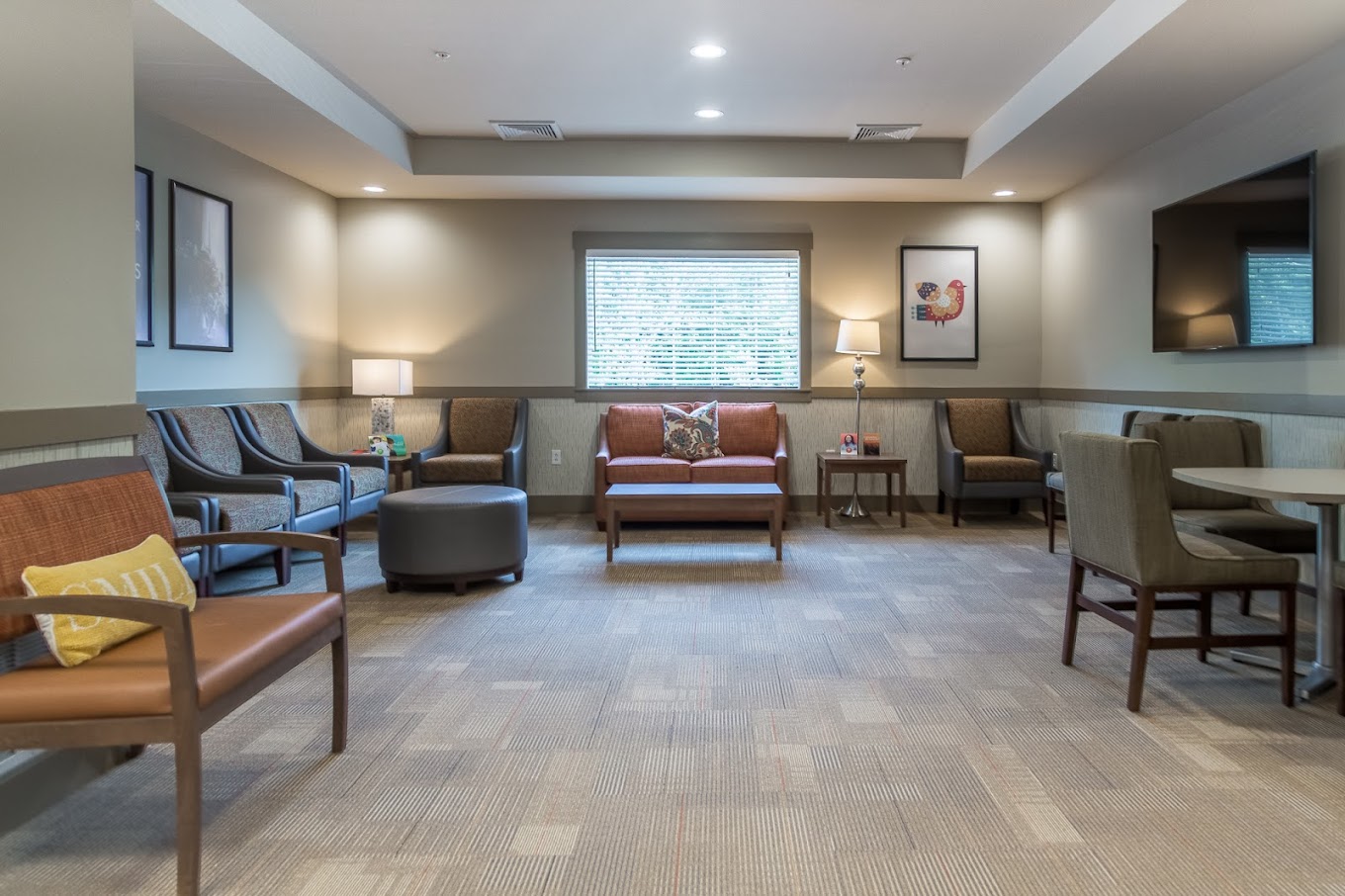 Spacious lounge with various seating, warm lighting, and a TV.