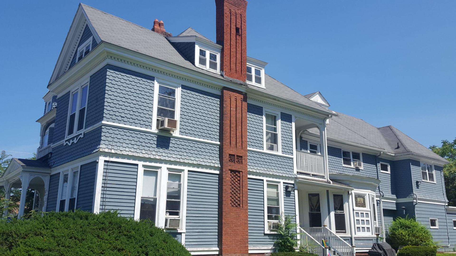 Blue home exterior with tall brick chimney