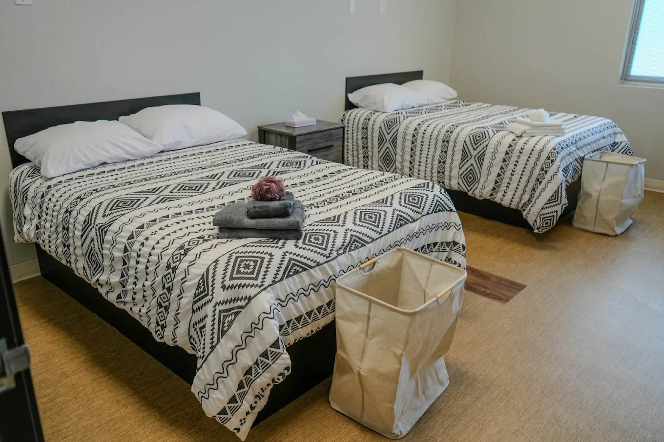 Two neatly made beds in a shared room with baskets
