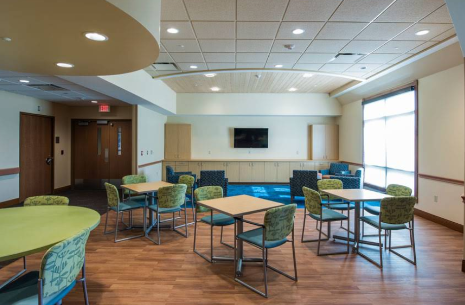 Open therapy space with tables, chairs, and wall-mounted TV