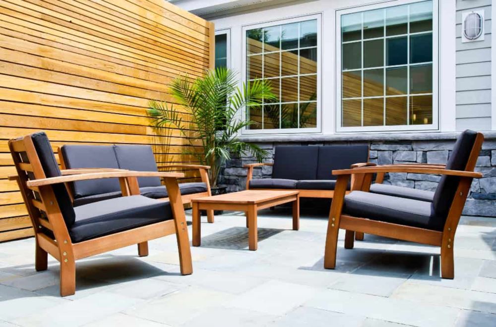 Wood patio furniture near privacy fence and windowed wall