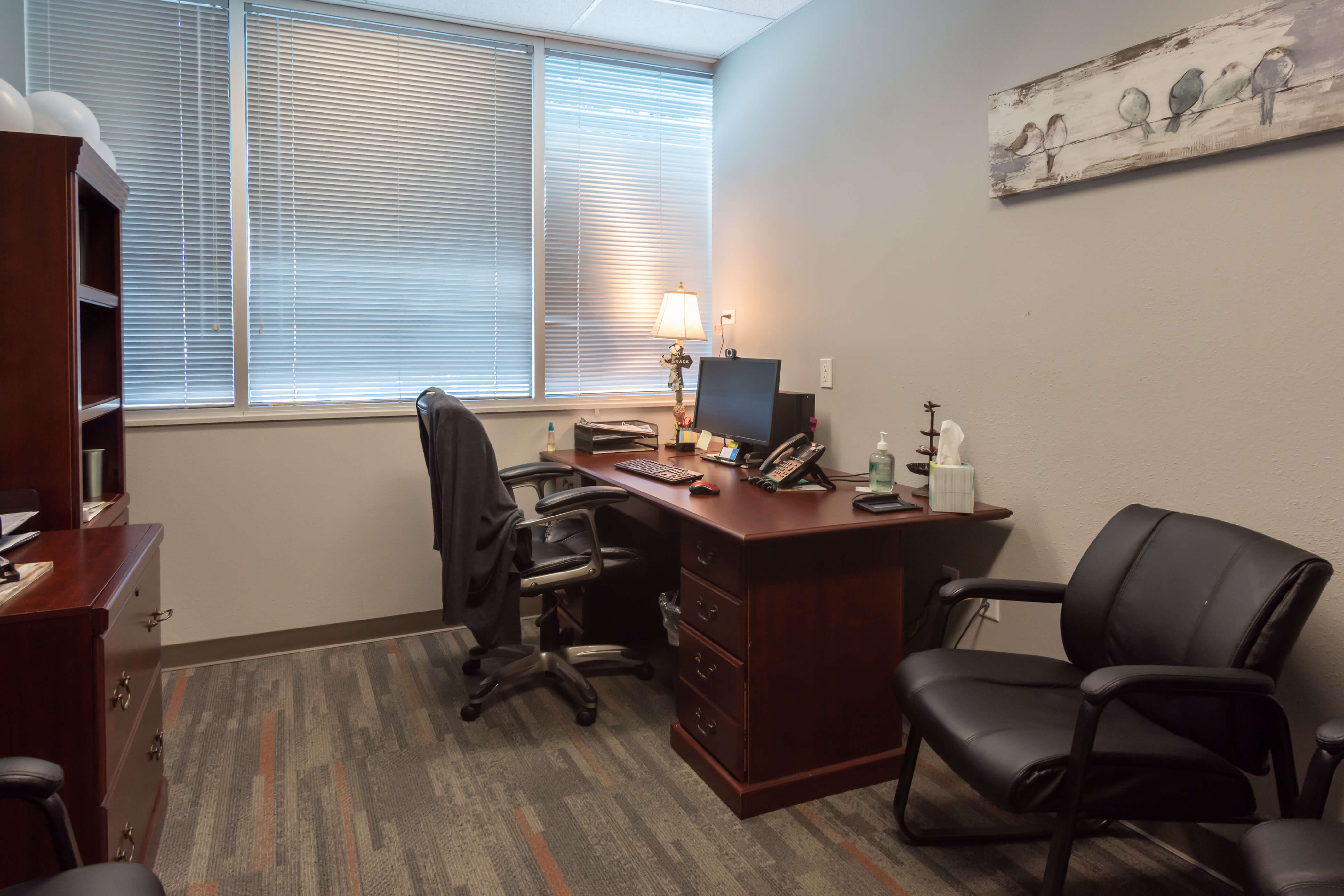 A professional office space with a desk, chair, and window blinds.