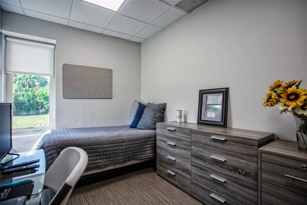 Private bedroom with bed, dresser, and desk