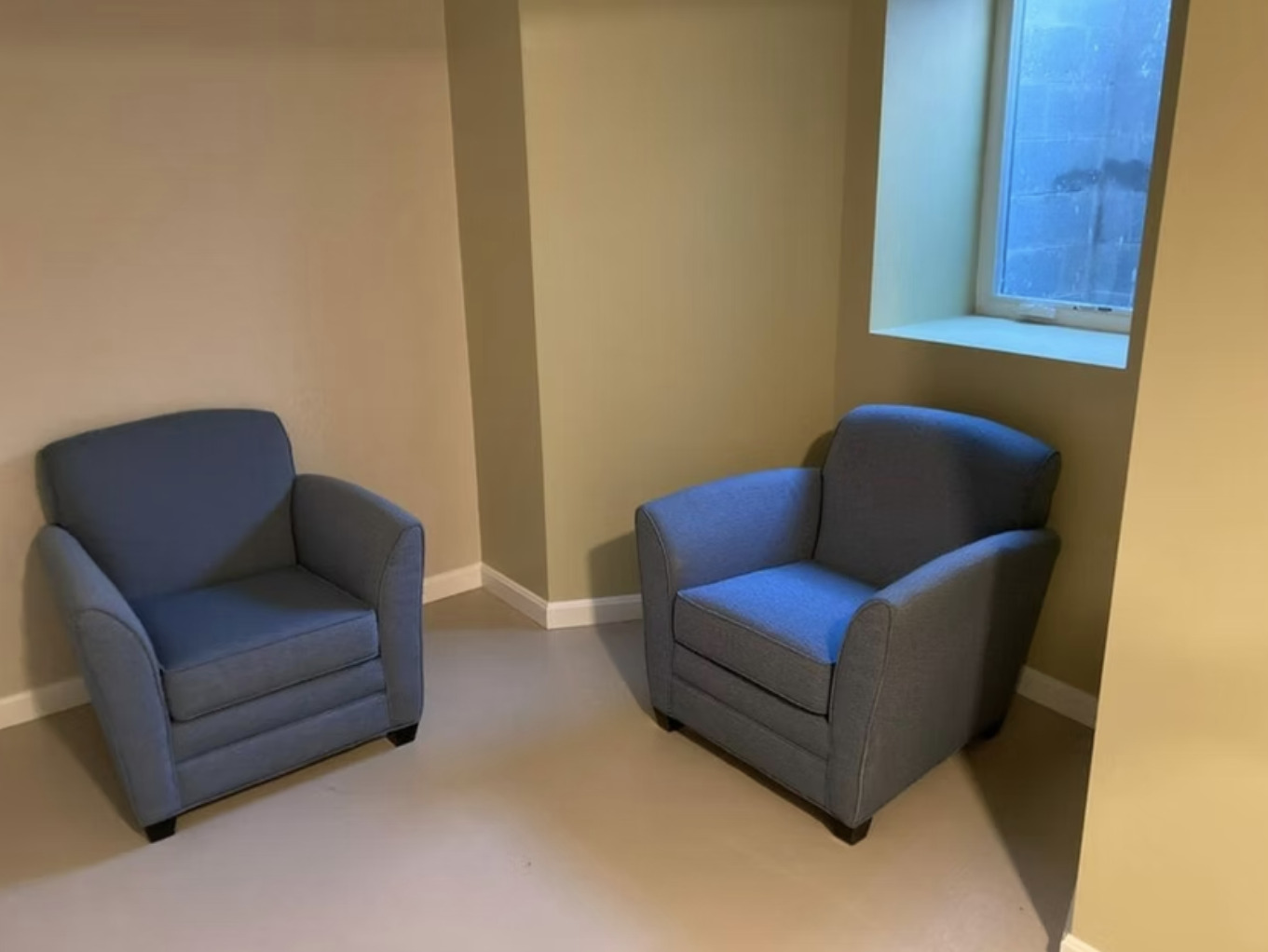 Small corner room with two blue armchairs and window