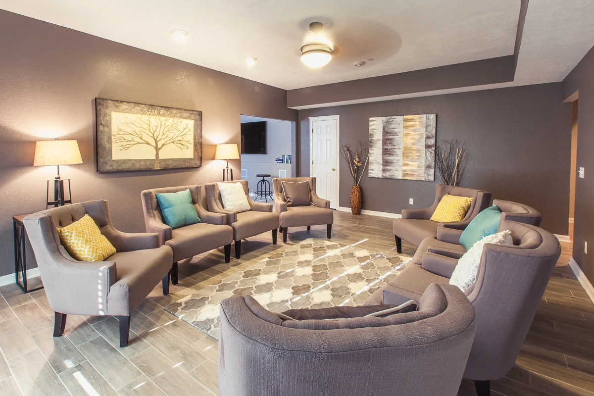 Circular arrangement of cushioned chairs in a softly lit room with abstract wall art and a neutral color scheme