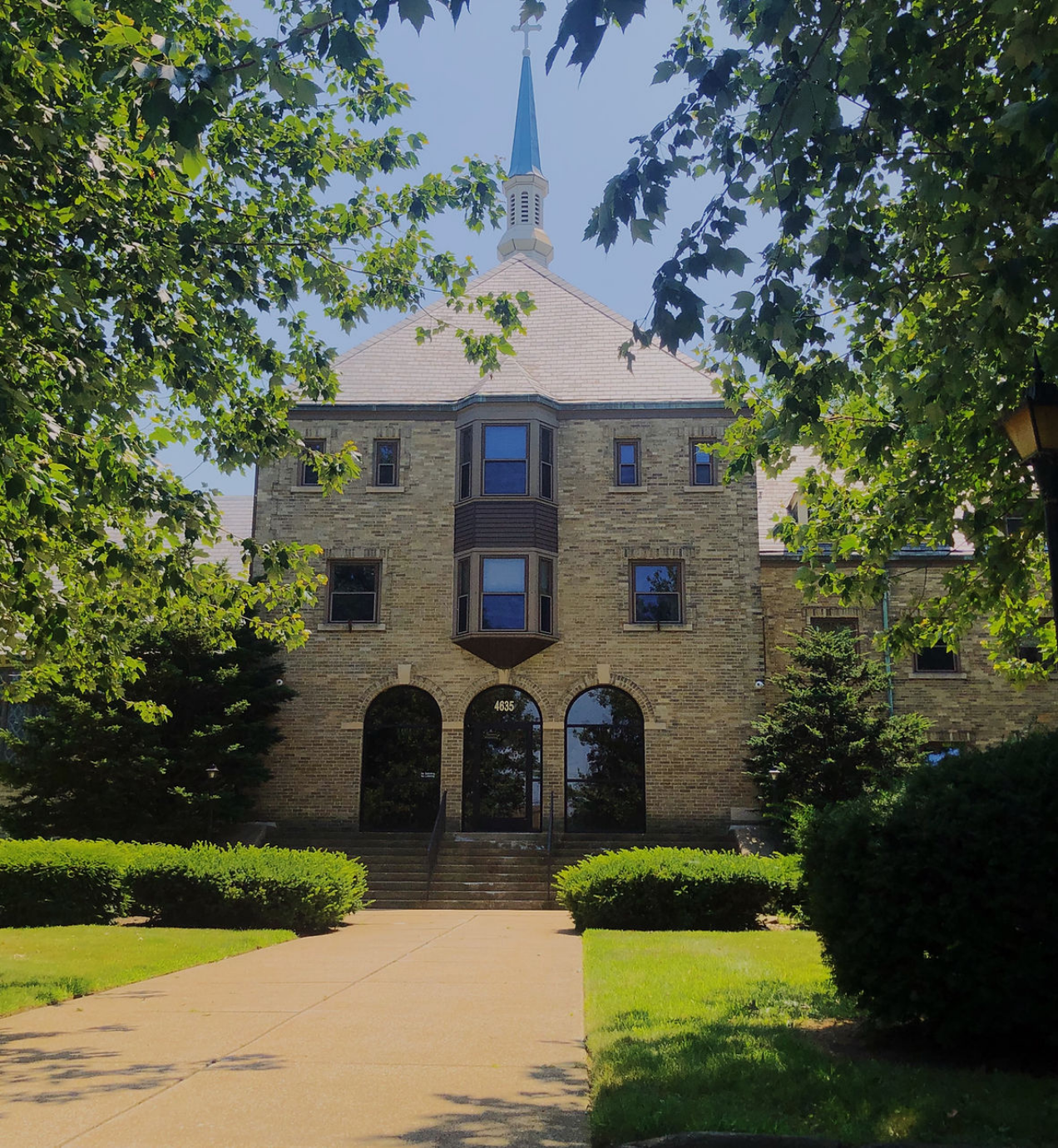 Brick building with central steeple and arched glass entry