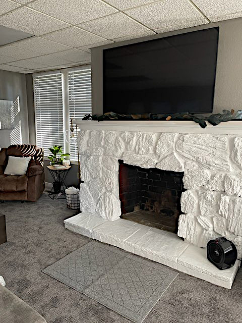 White stone fireplace with TV above and cozy seating area