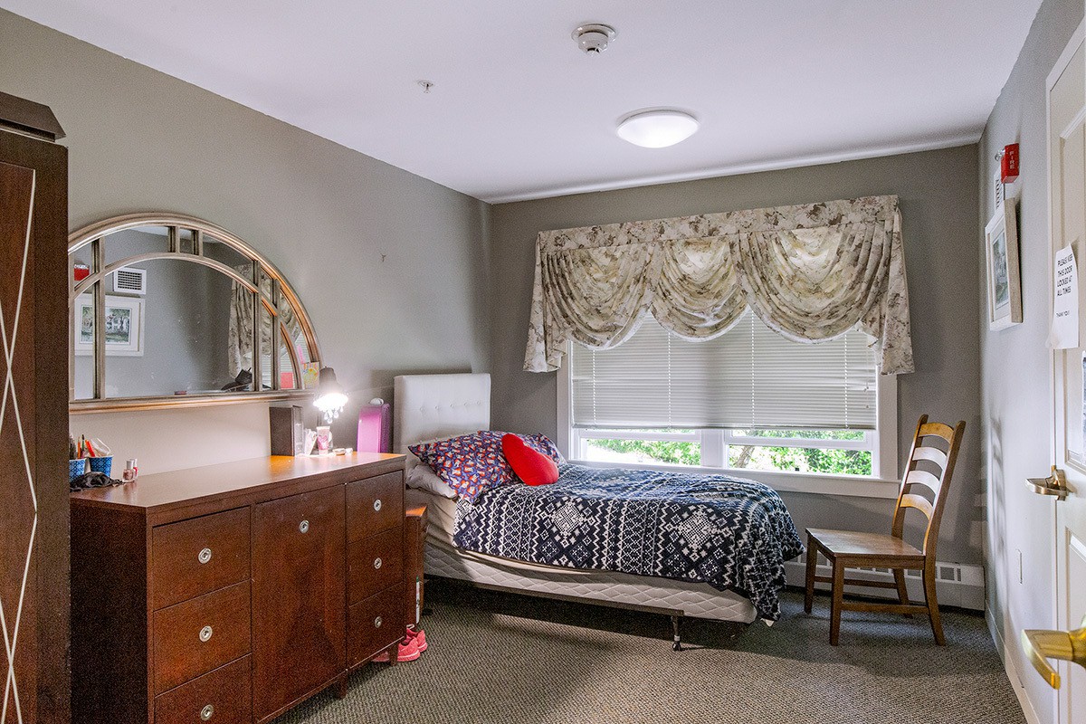 Single bedroom with dark wood dresser and floral curtains