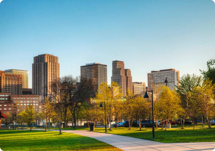 City skyline behind a park path and trees at golden hour