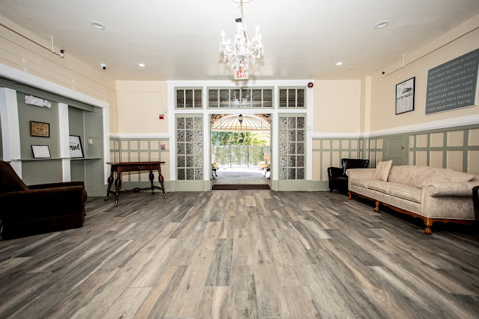 A spacious lounge with seating, wooden floors, and a chandelier.