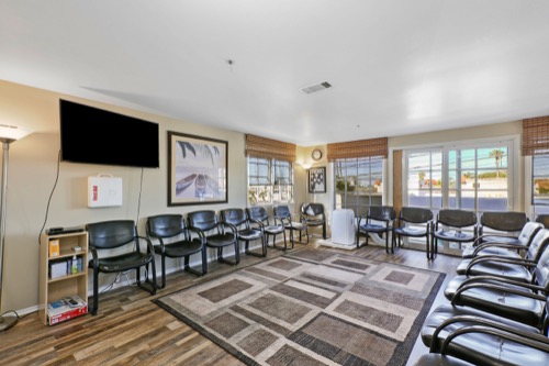 Group therapy room with circle of chairs and a flat-screen TV