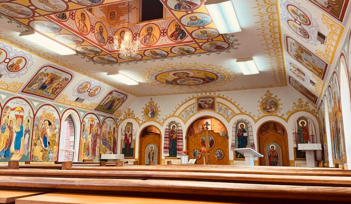 Interior of chapel with detailed religious murals and wooden pews
