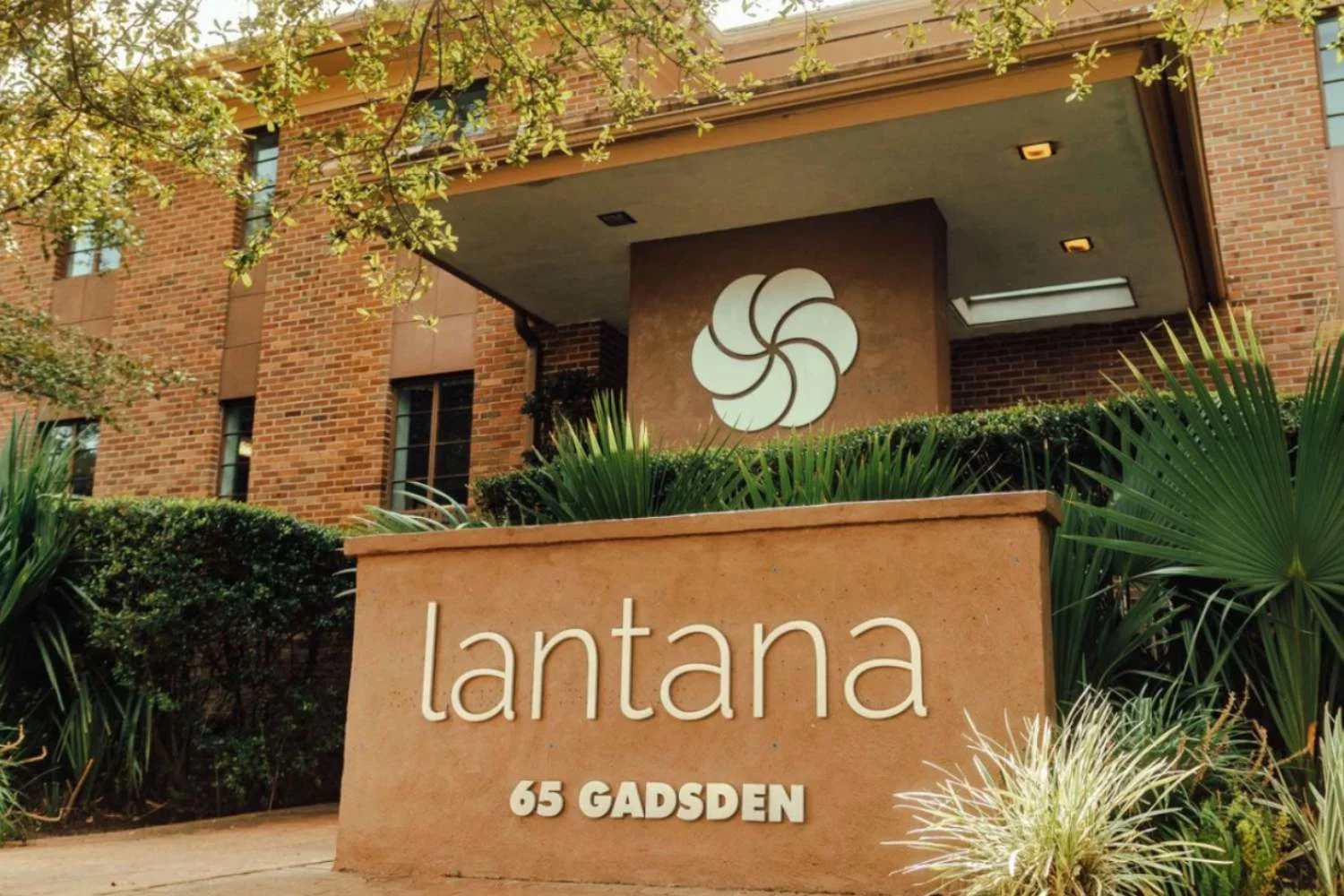 Lantana Recovery entrance sign with greenery and brick building.