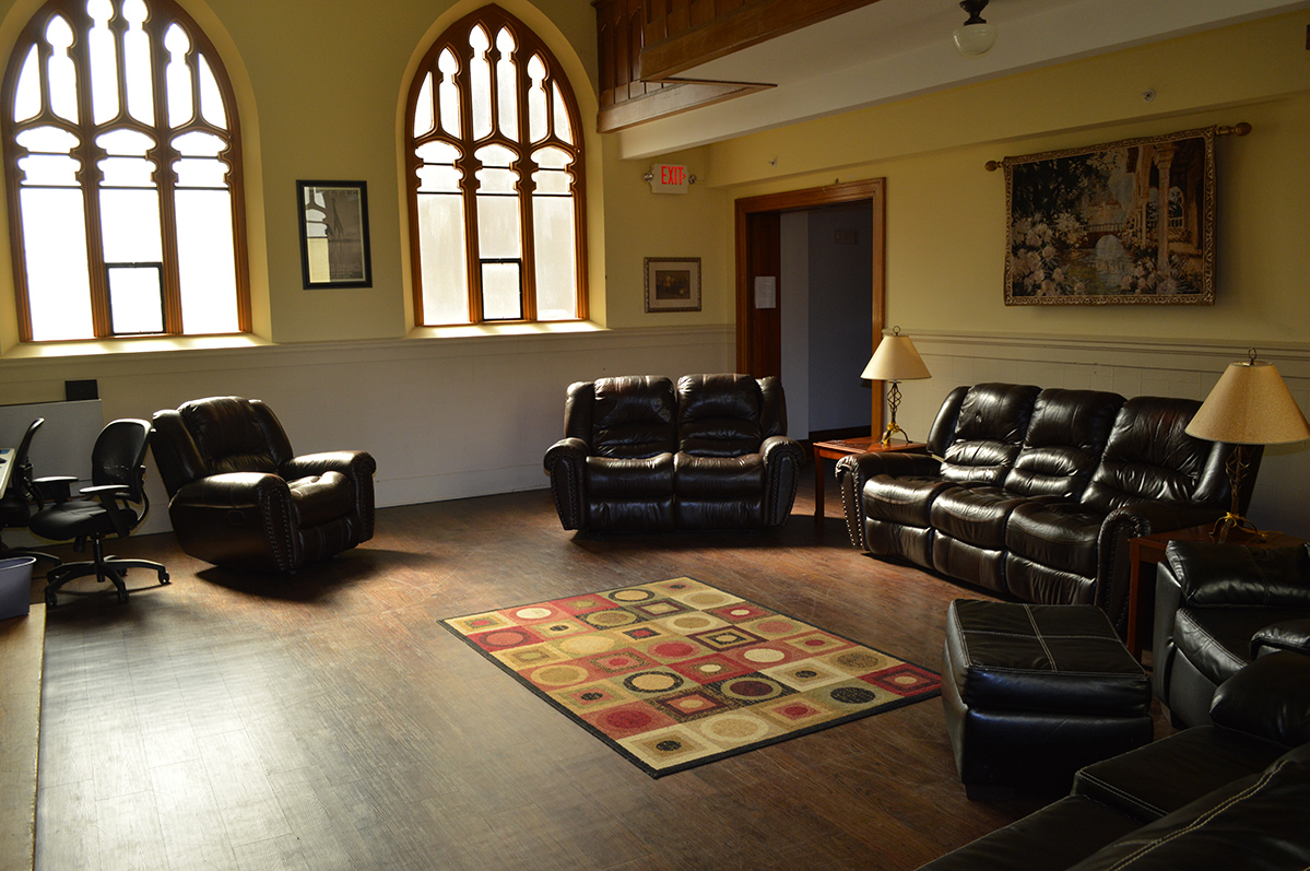 Large lounge with multiple leather couches, recliners, and tall arched windows
