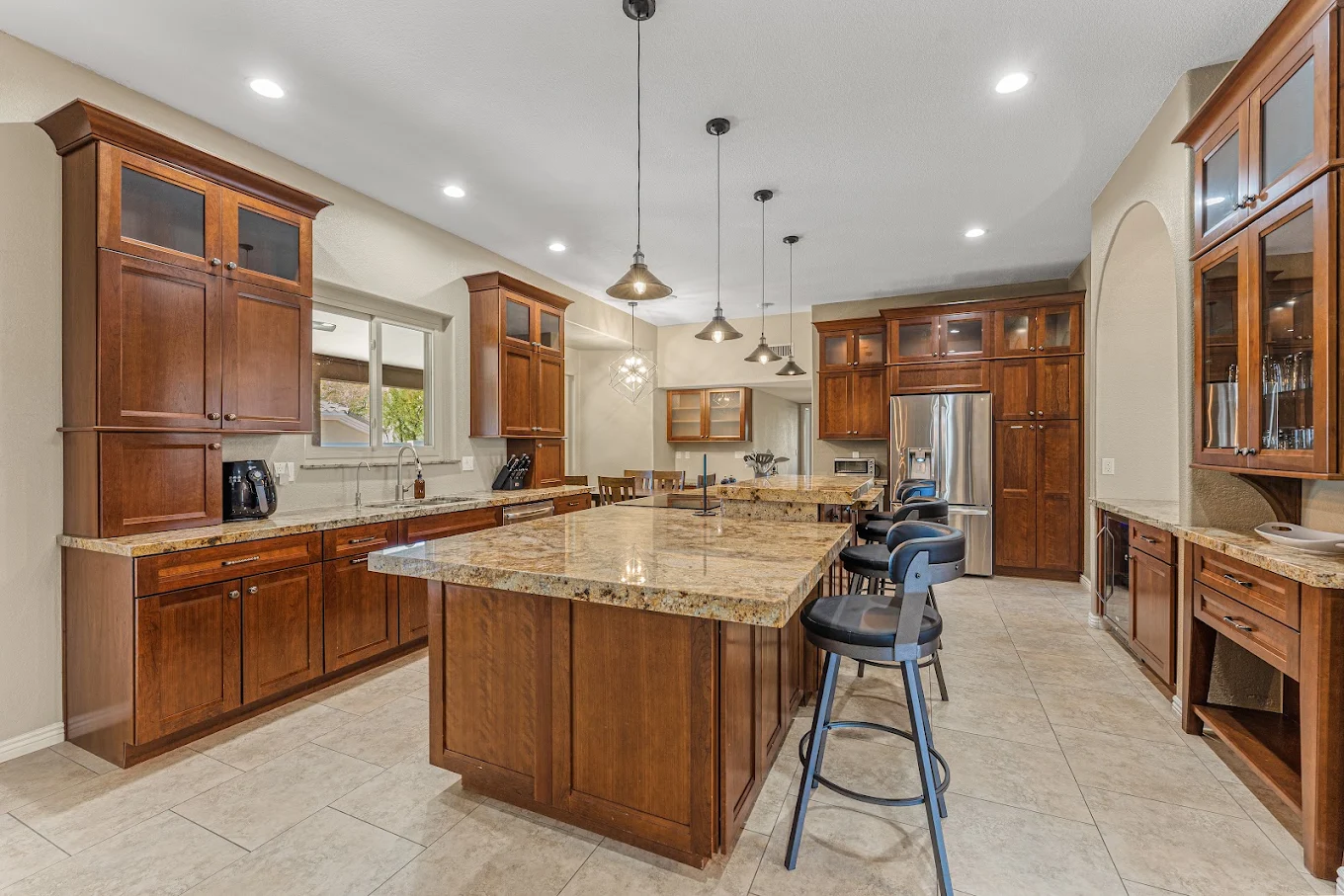Large kitchen with wood cabinets, granite counters, and island seating.