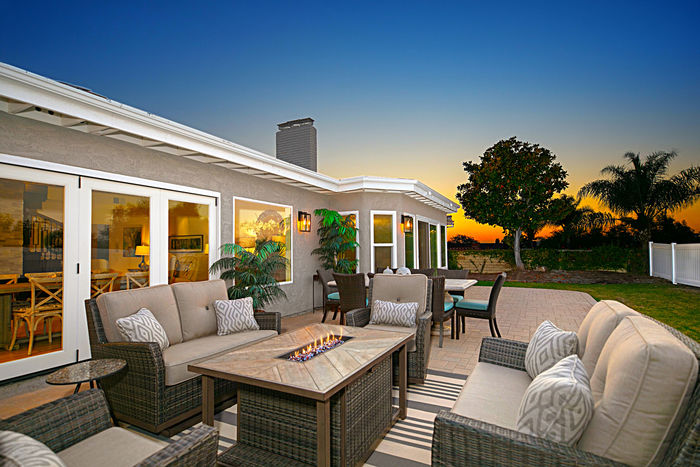 Outdoor patio with fire pit and lounge seating at sunset
