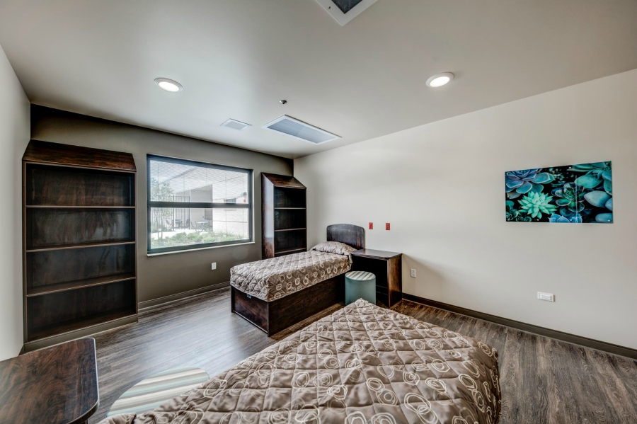 Two beds with shelves and a large window