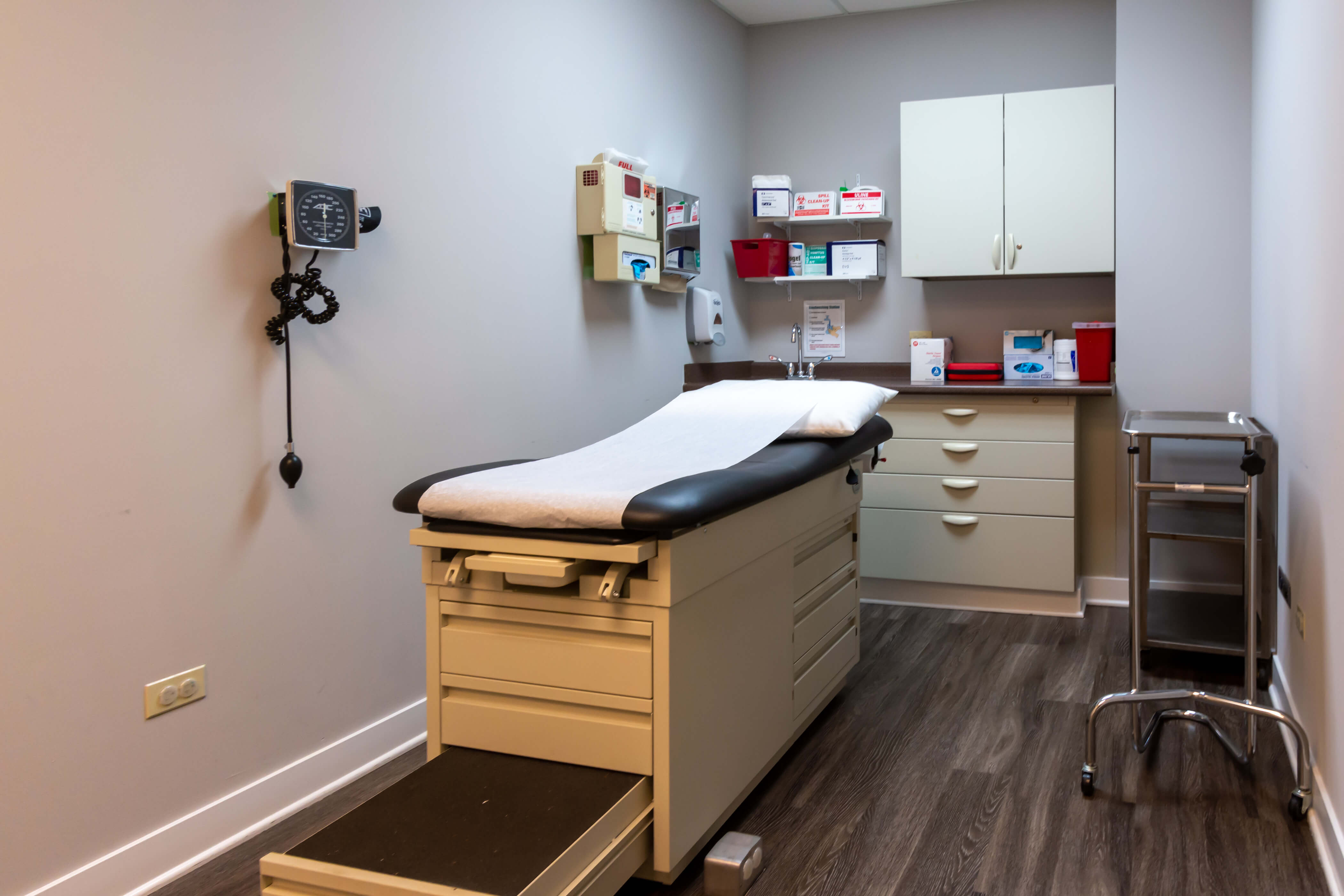 A medical exam room with a patient bed and cabinets.
