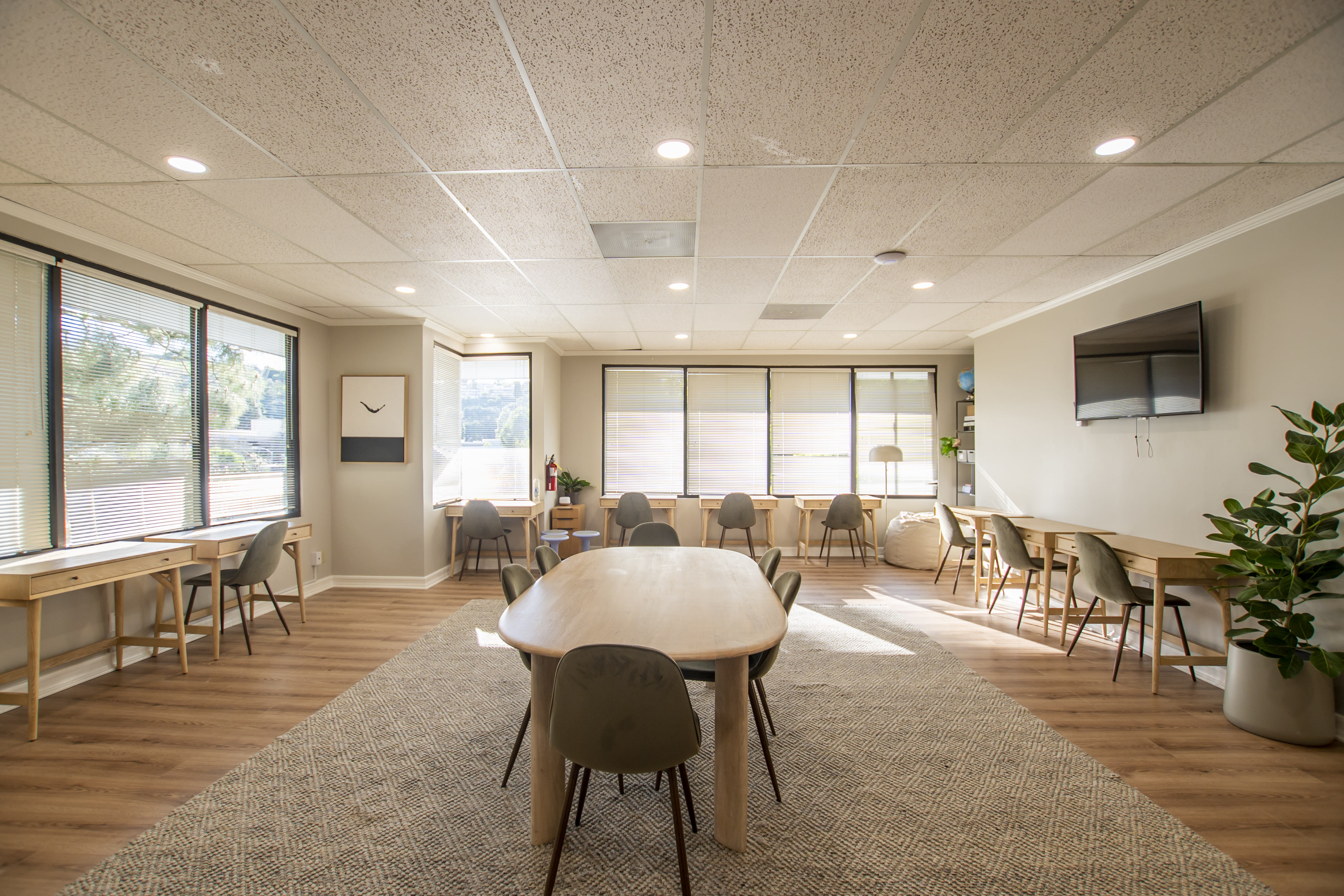 Spacious study area with multiple desks, chairs, and large windows