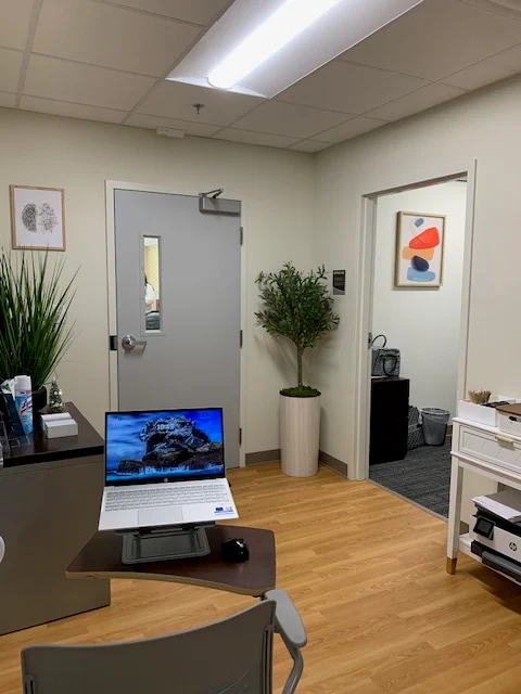 Reception area with desk, laptop, seating, and plants