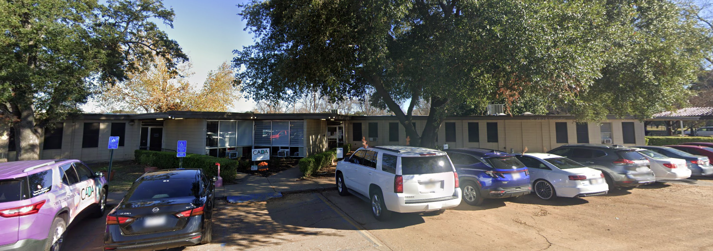 One-story treatment center with parking lot and large trees