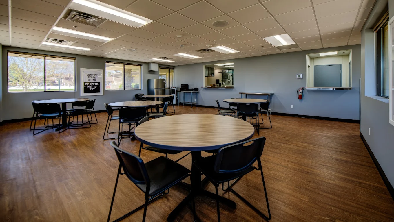 Dining room with round tables, chairs, and serving window