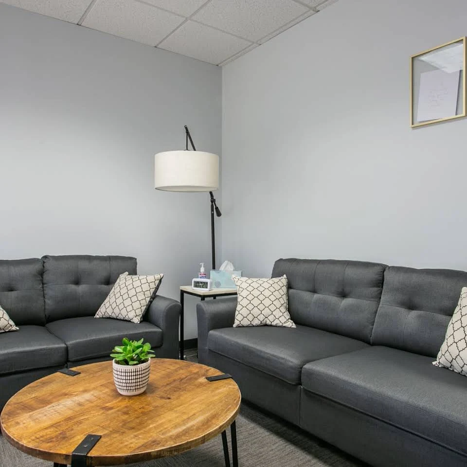 Counseling lounge with gray sofas and round wooden table