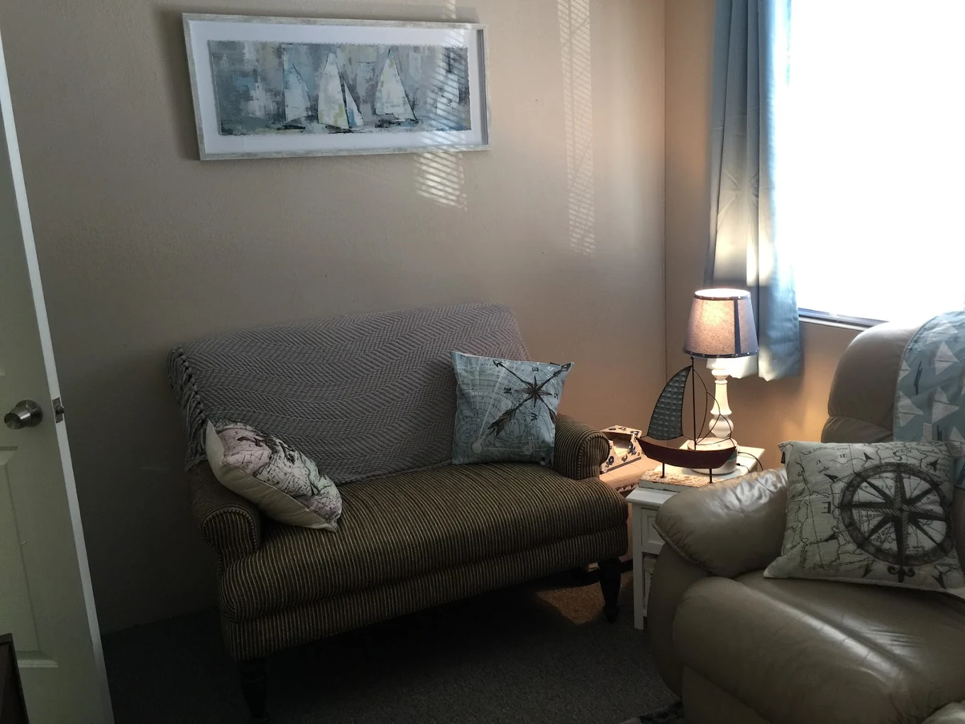 Sitting area with sailboat decor and striped loveseat