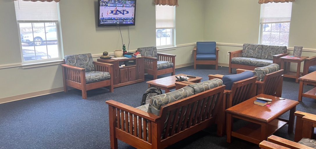 Lounge with wooden-framed seating, blue cushions, tables, and a wall-mounted TV