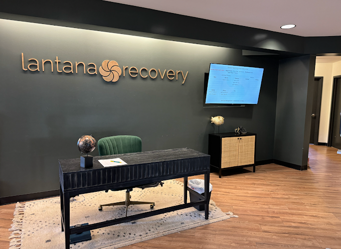 Reception desk in lobby with logo wall and TV