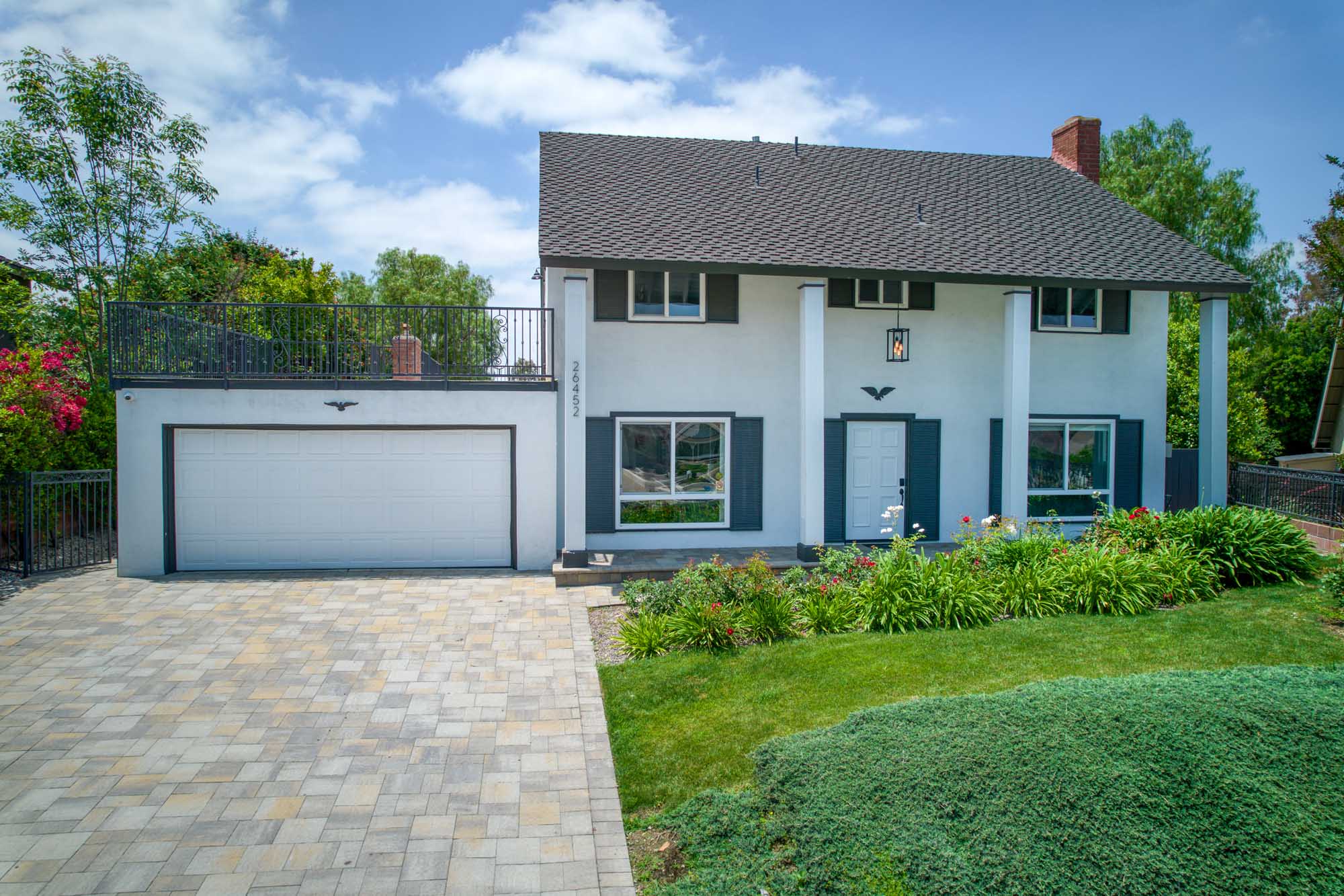 Two-story house with columns, garden, and stone driveway
