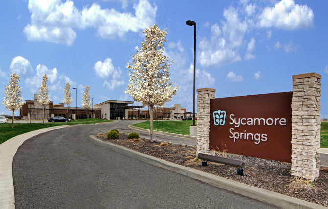 Driveway leading to Sycamore Springs sign and building