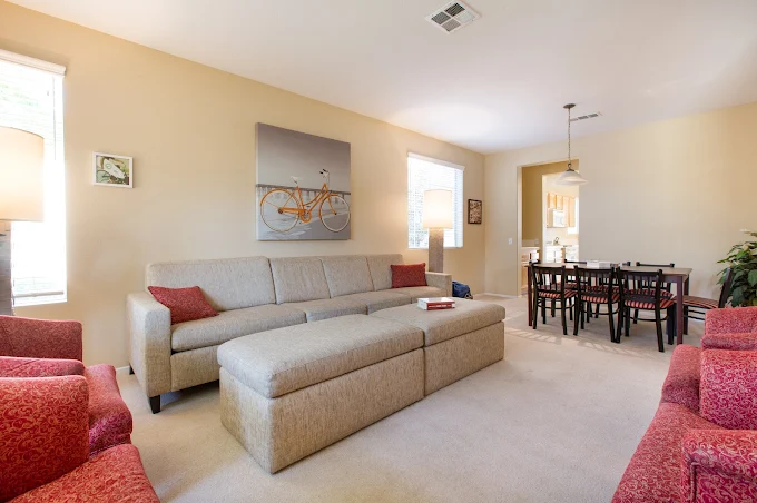 Living space with gray sectional and red accent chairs