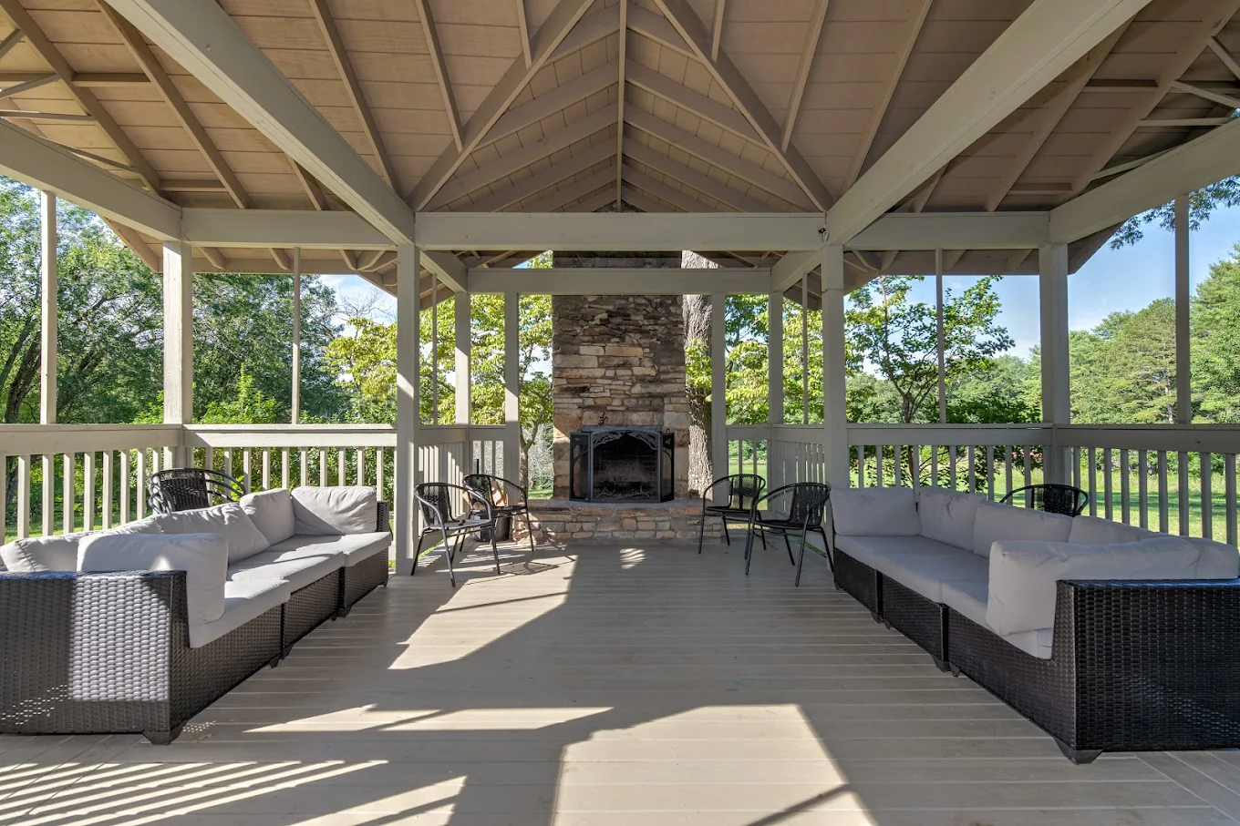 Shaded outdoor seating area with sofas and stone fireplace