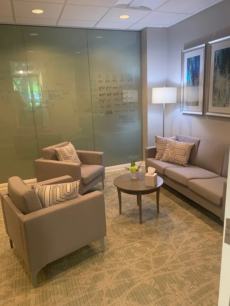 Private therapy room with chairs, sofa, and glass wall