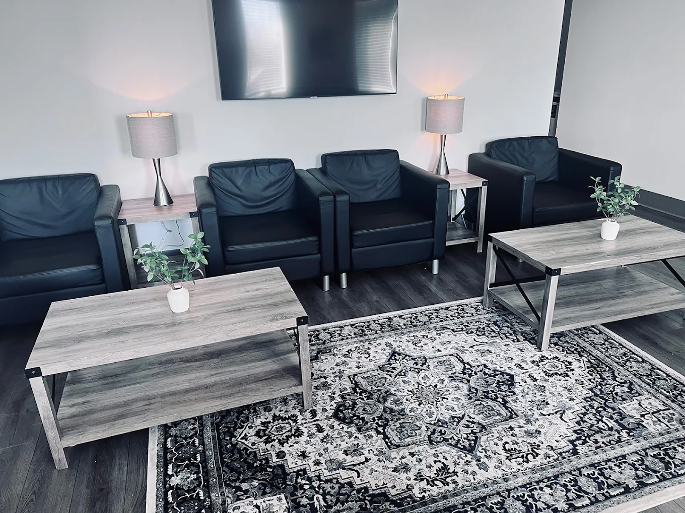 Lounge-style sitting area with black armchairs, coffee tables, and a patterned rug