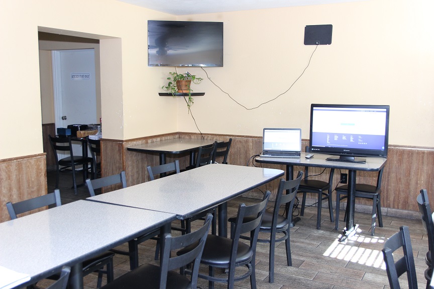 Group therapy room with tables, chairs, and two TVs